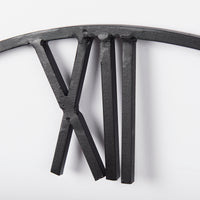 up close shot of black metal roman numeral on wall clock for sale - r. home co.